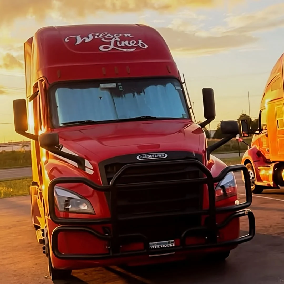 A red Wilson Lines truck parked in warm sunset light.